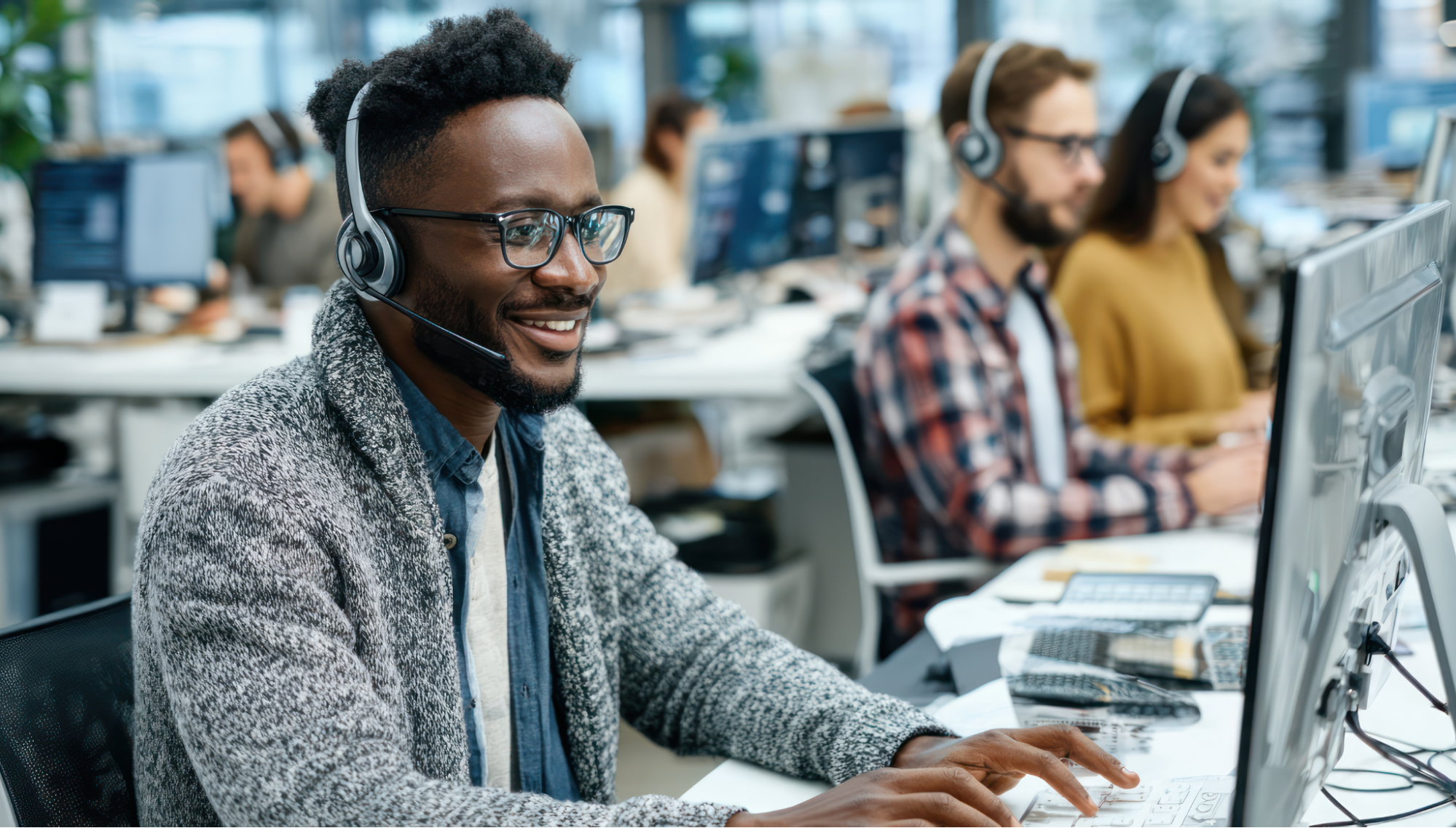 Illustration of employees working in an in-house call center with headsets and computers.